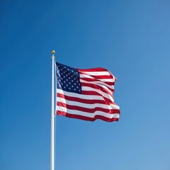 Naklejka premium American flag waving high against clear blue sky. Flag on white pole flies proud with red, white, and blue stripes. Symbol of US, American nation, freedom, independence.