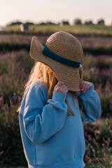 red haired girl in a straw hat in a lavender field at sunset