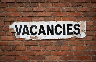 Obraz premium Brick wall exterior with vacant property notice in white lettering. Text VACANCIES displayed prominently on brick surface. Rustic brick texture and empty sale or advertisement message.