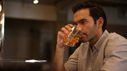 Sitting smart man drinking alone of cocktail Old fashioned waiting friends or couple at bokeh lighting at luxurious beverage counter nightclub at pub and restaurant on Friday meeting night. Vinosity.
