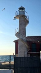 photo of a car standing on the seashore, a seagull flying over it, bird, building, lighthouse, summer, vacation, spiral staircase