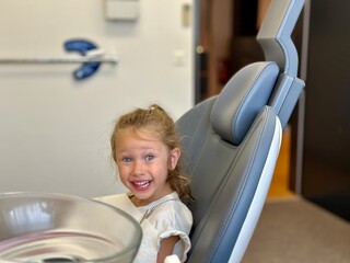 little girl sitting on a chair. A little girl in a dental office for a dental checkup and treatment 