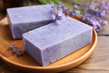 Soap bars and lavender flowers on wooden table, closeup