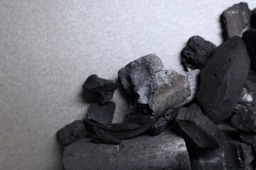 Pieces of black coals on grey table, top view. Space for text