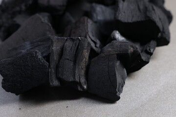 Pieces of black coals on grey table, closeup