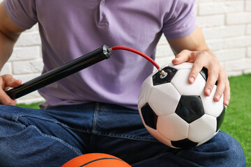 Man inflating soccer ball with manual air pump indoors, closeup