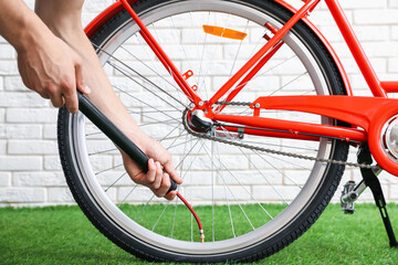 Man inflating bicycle tire with manual air pump indoors, closeup