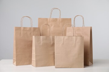 Kraft paper bags on table against grey background