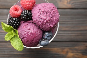 Delicious sorbet with fresh berries and mint in bowl on wooden table, top view. Space for text