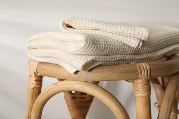Folded waffle towels on wicker chair near light wall, closeup