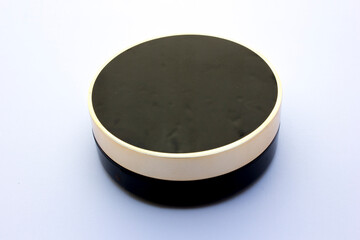 Black circular tube powder compact isolated on the white background.