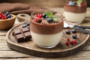 Delicious panna cotta with chocolate, berries and mint on wooden table, closeup