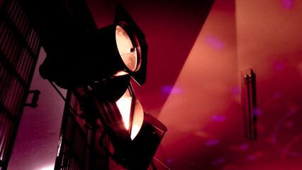 Two theatrical PAR can spotlights—one casting red light and the other pink—illuminate an art...