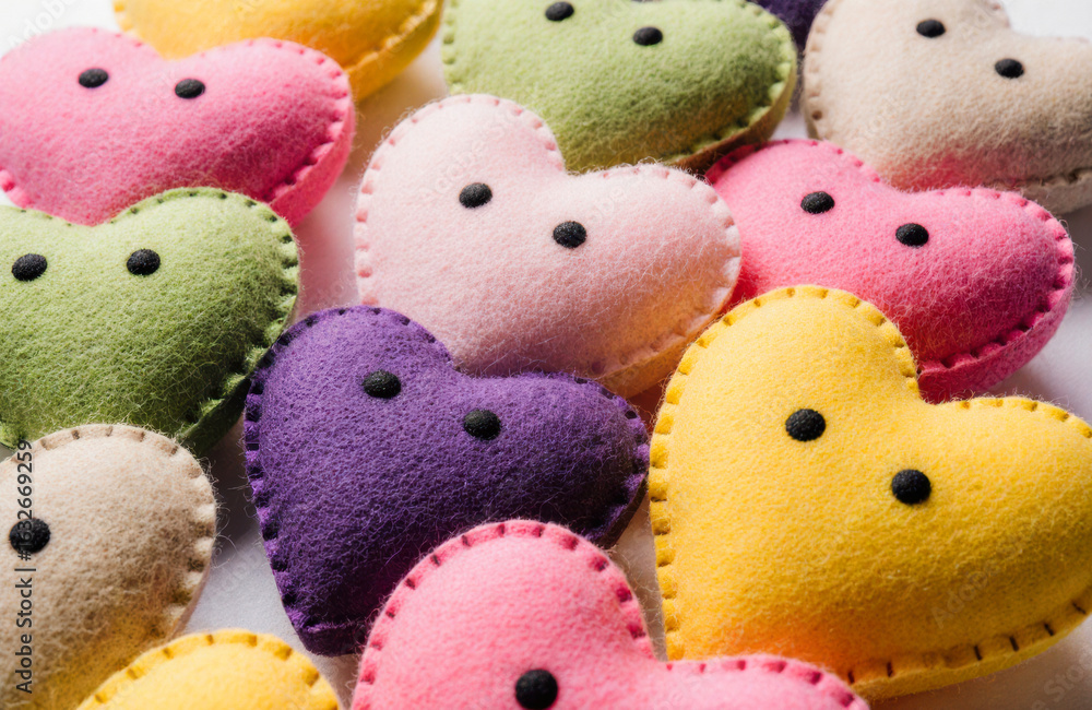 Poster colorful felt hearts with stitched edges and button eyes arranged in a close-up view
