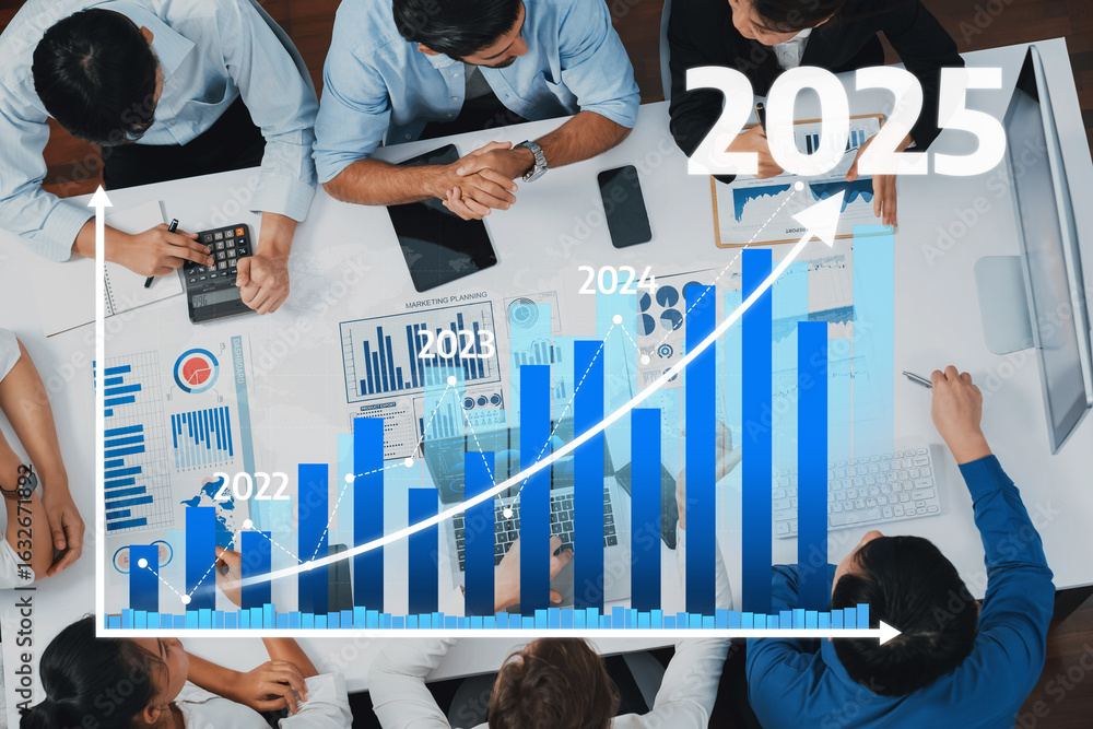 Poster a business team collaborates over a table filled with technology while analyzing a growth chart for 
