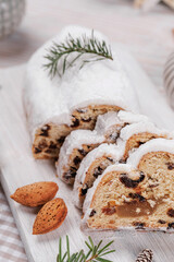 A delightful display of stollen bread sliced and dusted with powdered sugar, accented by almonds, ornaments, and festive holiday decorations.