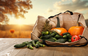 Autumn vegetables in canvas bag on wooden table with fall sky background and empty copy space for...
