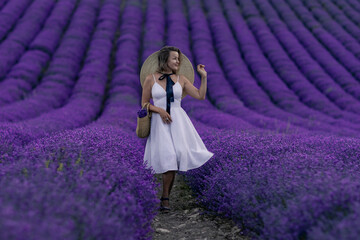 A woman is walking through a field of purple flowers