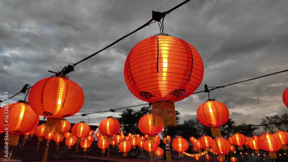 Poster a bunch of orange lanterns hanging from a wire. some of them are lit up. there are many of them