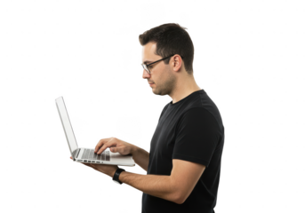 A man with glasses using a laptop while standing in a dark environment with focused expression on transparent background