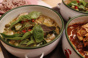 An authentic bowl of spicy Thai green curry with basil and eggplant served with rice.

