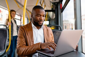 Man working on laptop during commute on bus public transportation technology job
