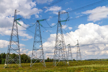 High voltage power transmission towers in rural area under blue sky.