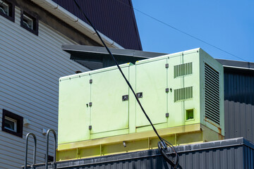Rooftop view of weathered light green industrial generator or HVAC unit mounted on yellow base...