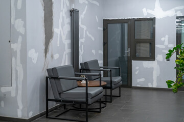 Modern grey armchairs with wooden table in contemporary minimalist interior featuring light grey...