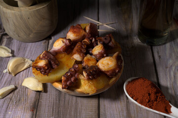 Traditional Spanish tapa of octopus with potatoes, paprika and garlic on rustic wooden table. Typical Galician dish called 