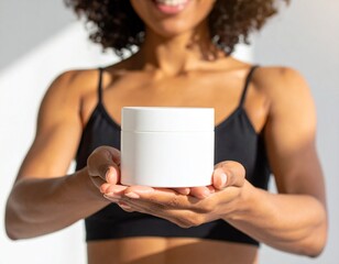 A fit woman with glowing brow skin holds a white jar cosmetic