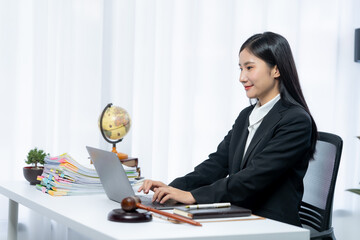Focused Professional at Desk: An attractive young woman is immersed in her work at a modern desk,...