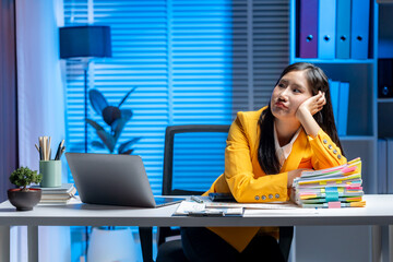 Bored at the Office: A professional in a vibrant yellow jacket, seated at her office desk, appears...
