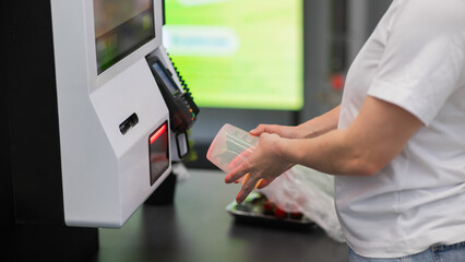 Obraz premium A woman scans items at a self-checkout. 