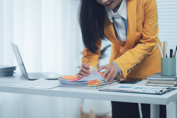 Overwhelmed by Paperwork: A businesswoman grapples with a towering stack of documents, her desk cluttered with the tools of a demanding profession, evoking the stress of deadlines and administrative o