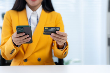 Digital Commerce: A modern woman in an elegant yellow suit, poised and focused, navigates the digital realm, seamlessly managing her finances using a sleek smartphone and a secured credit card.