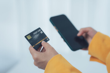 Digital Commerce: A person's hands deftly hold a sleek credit card and a mobile phone, embodying modern digital transactions and effortless financial management.