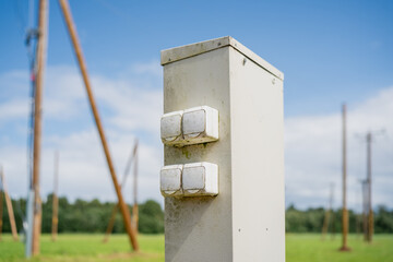 Outdoor electrical switchboard with multiple sockets in rural area, utility infrastructure for temporary power supply near power lines under blue sky