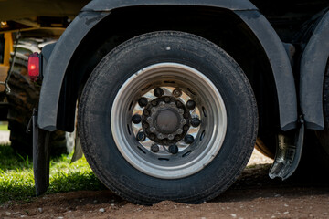 Heavy-duty truck wheel and tire on gravel road, transportation and logistics detail with rubber tread and metal rim