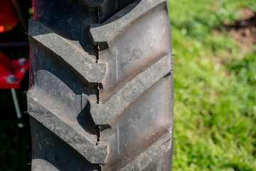 Large tractor tire tread pattern, heavy-duty agricultural wheel, rugged rubber texture for farming or construction equipment, outdoor rural environment
