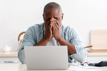Lack of money concept. Stressed black man checking bills, managing household budget or expenses,...