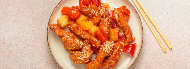 Asian delicious sweet and sour chicken garnished with sesame seeds, pineapple chunks, and bell...