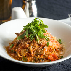 Delicious Caprese Pasta with Fresh Arugula and Parmesan Cheese in plate closeup side view of Italian food