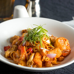 Spicy Seafood Spaghetti Mee Goreng with Prawns, Fishcake, and Scallions in bowl closeup side view of asian meal