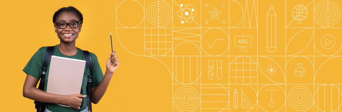 A young student stands confidently with a laptop and a pencil in a vibrant classroom. The bright walls and educational visuals enrich the atmosphere, promoting learning and creativity.