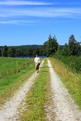 Woman walking at country road one summer day. Bergslagen, Sweden.