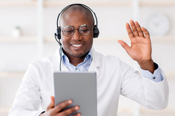 Modern digital technologies and consultation with therapist. Happy african american doctor waving...