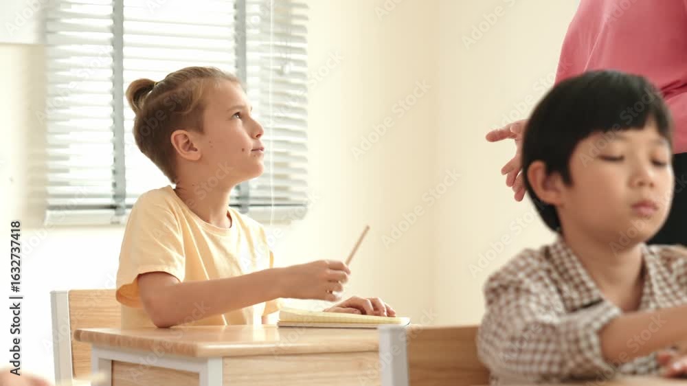 Poster beautiful teacher explaining test while caucasian boy doing classwork and listening explanation. cut