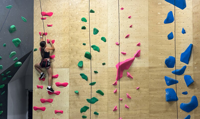 Teenage girl at indoor climbing wall. Kid having fun at bouldering wall. Child learning at climbing...