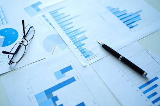 Analyzing business charts and graphs with pen and glasses for financial review